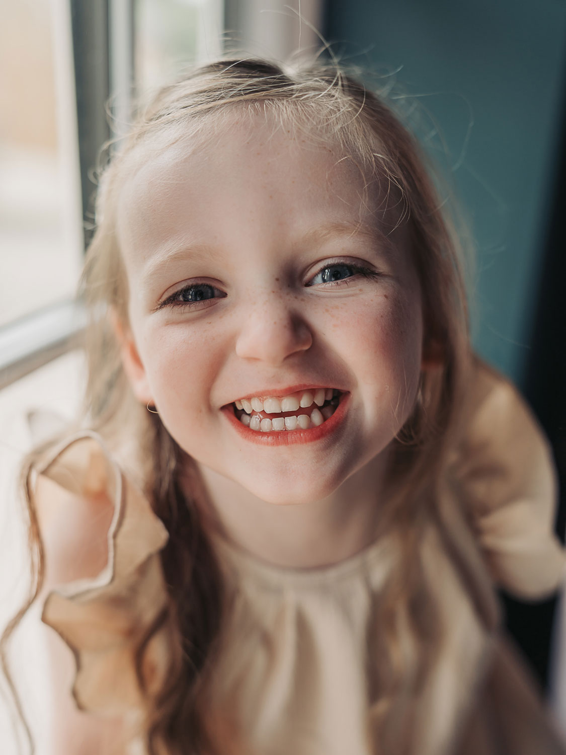 Close up of little girls face smiling at the camera at a newborn photoshoot by The Corbett Creative Photography