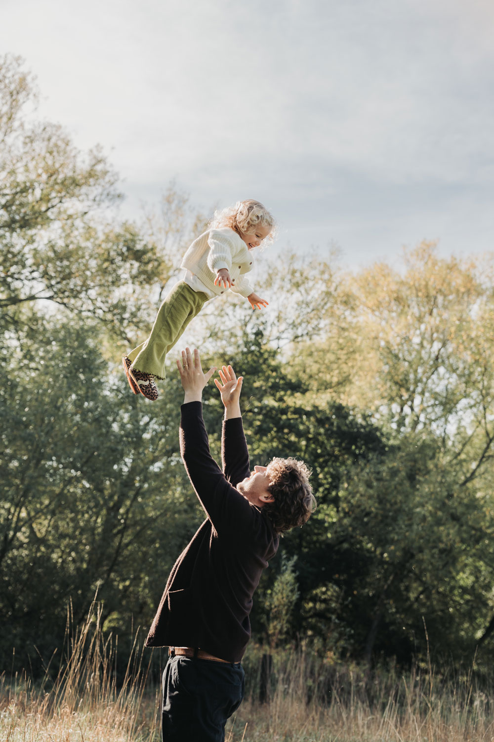 Dad throwing little girl up in the air during outdoor family photoshoot