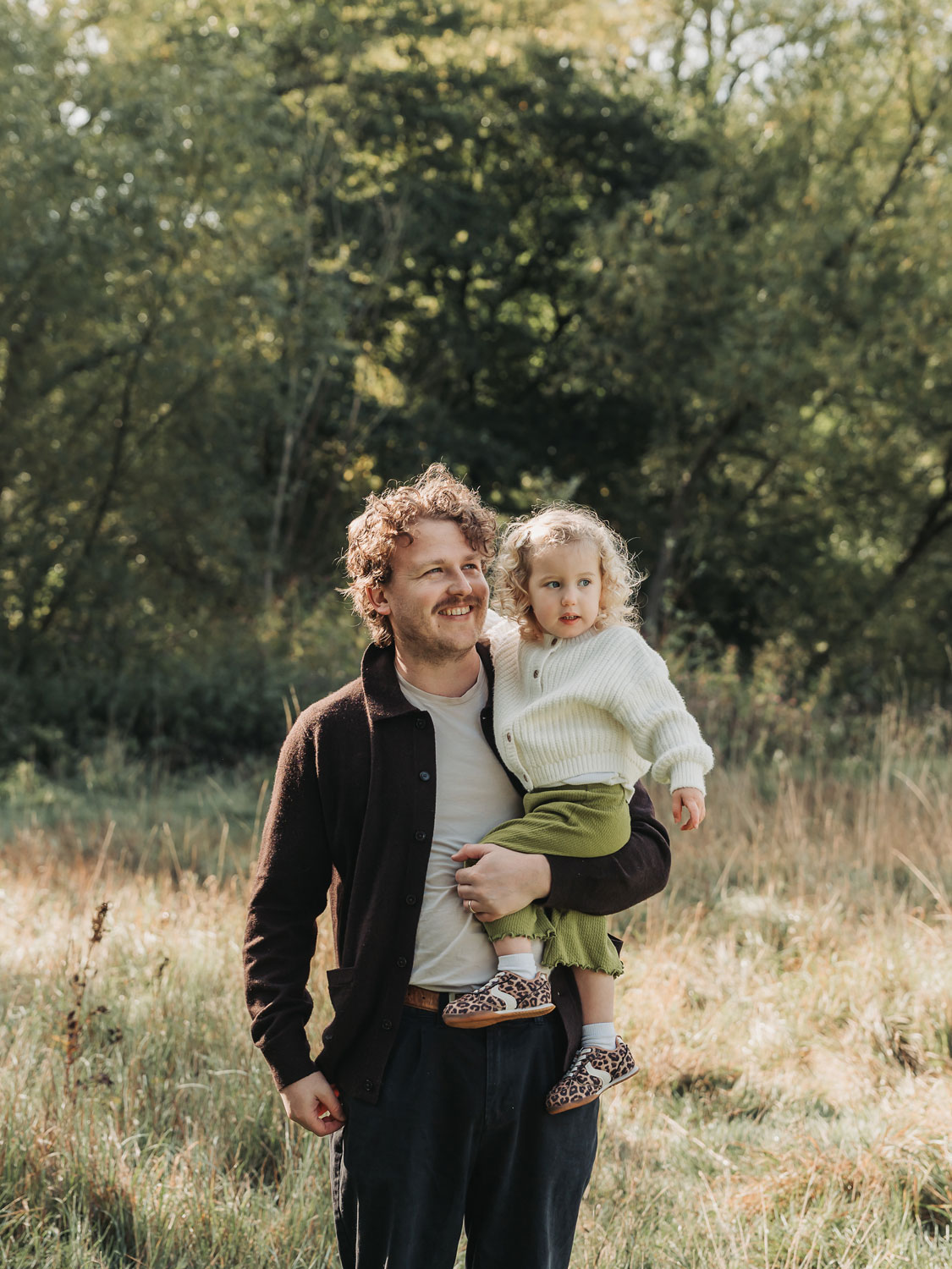 Dad holding little girl and smiling during an outdoor family photoshoot