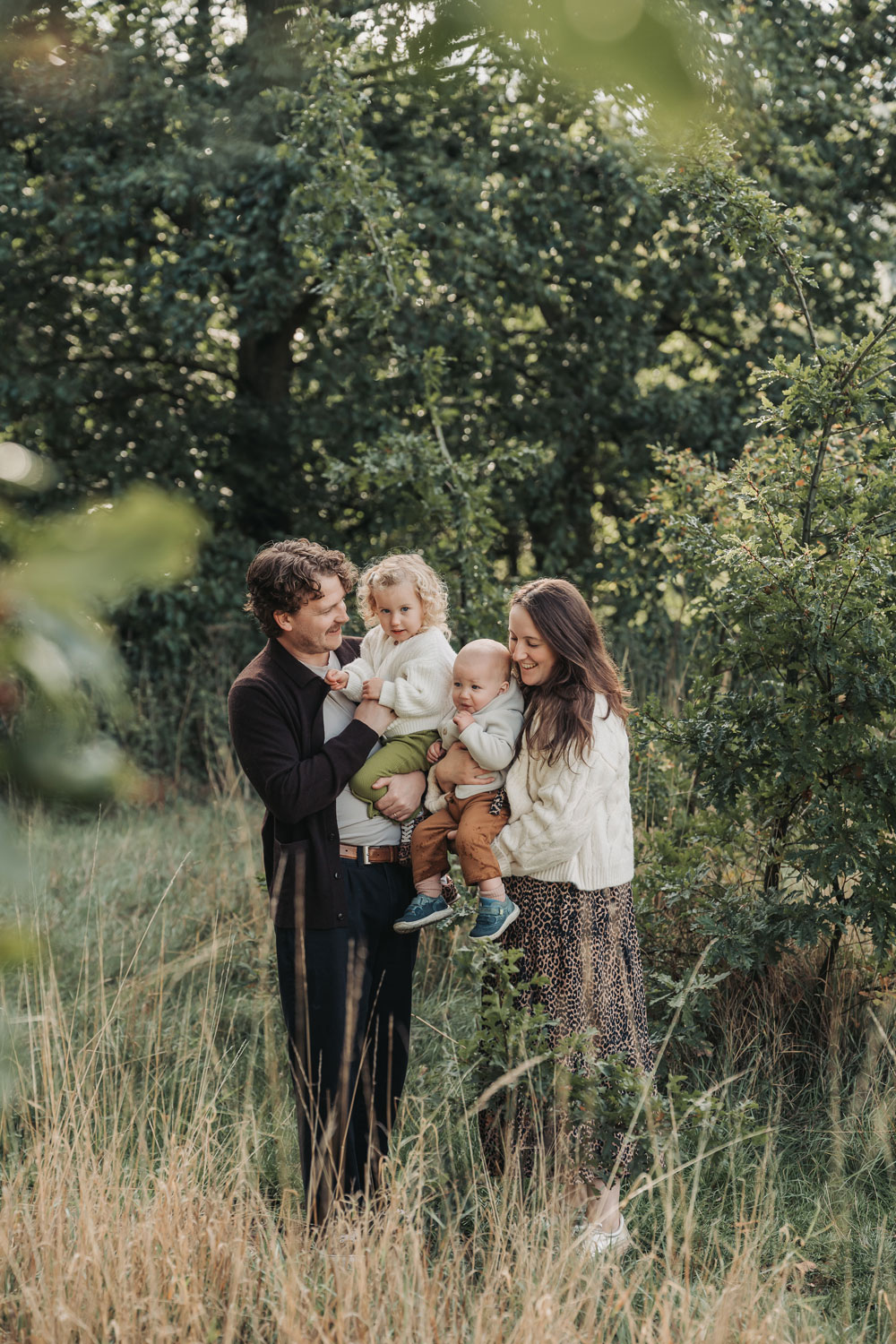 Family cuddling together in long grass at an outdoor family photoshoot in Warwickshire