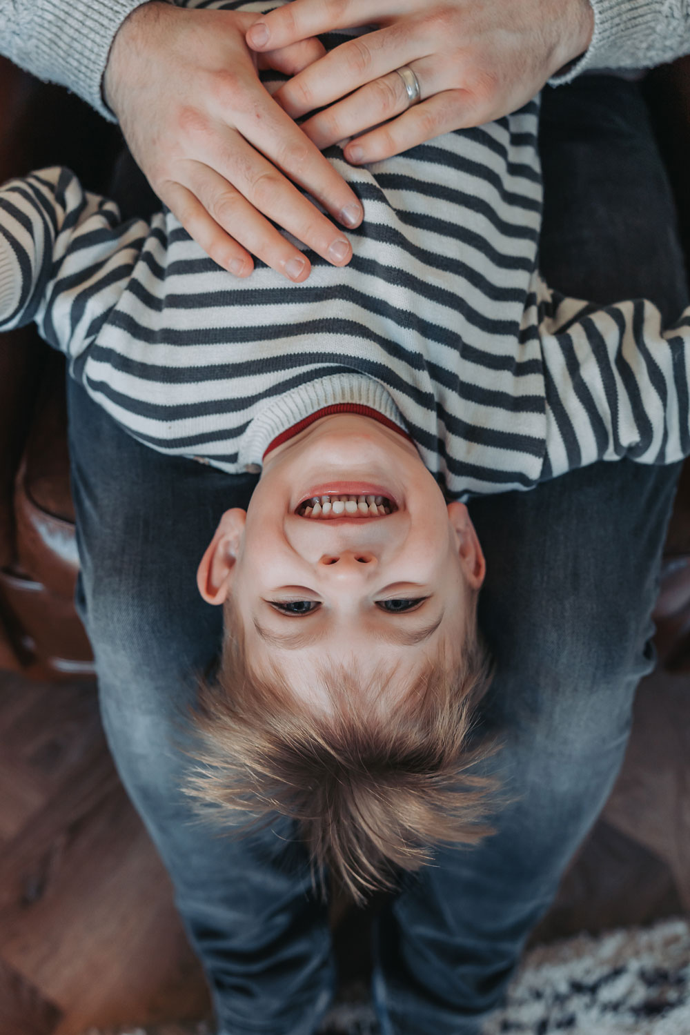 Upside down image of a boy smiling at the camera during an in home family photoshoot in Warwickshire