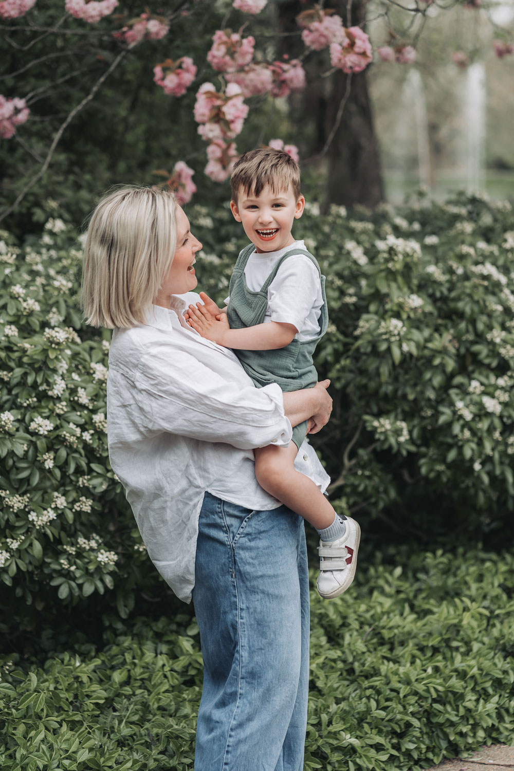 Mum cuddling happy boy with pink blossom tree in Jephson Gardens
