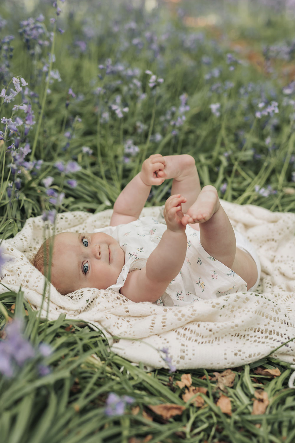Warwickshire outdoor bluebell family photoshoot with baby on blanket holding feet