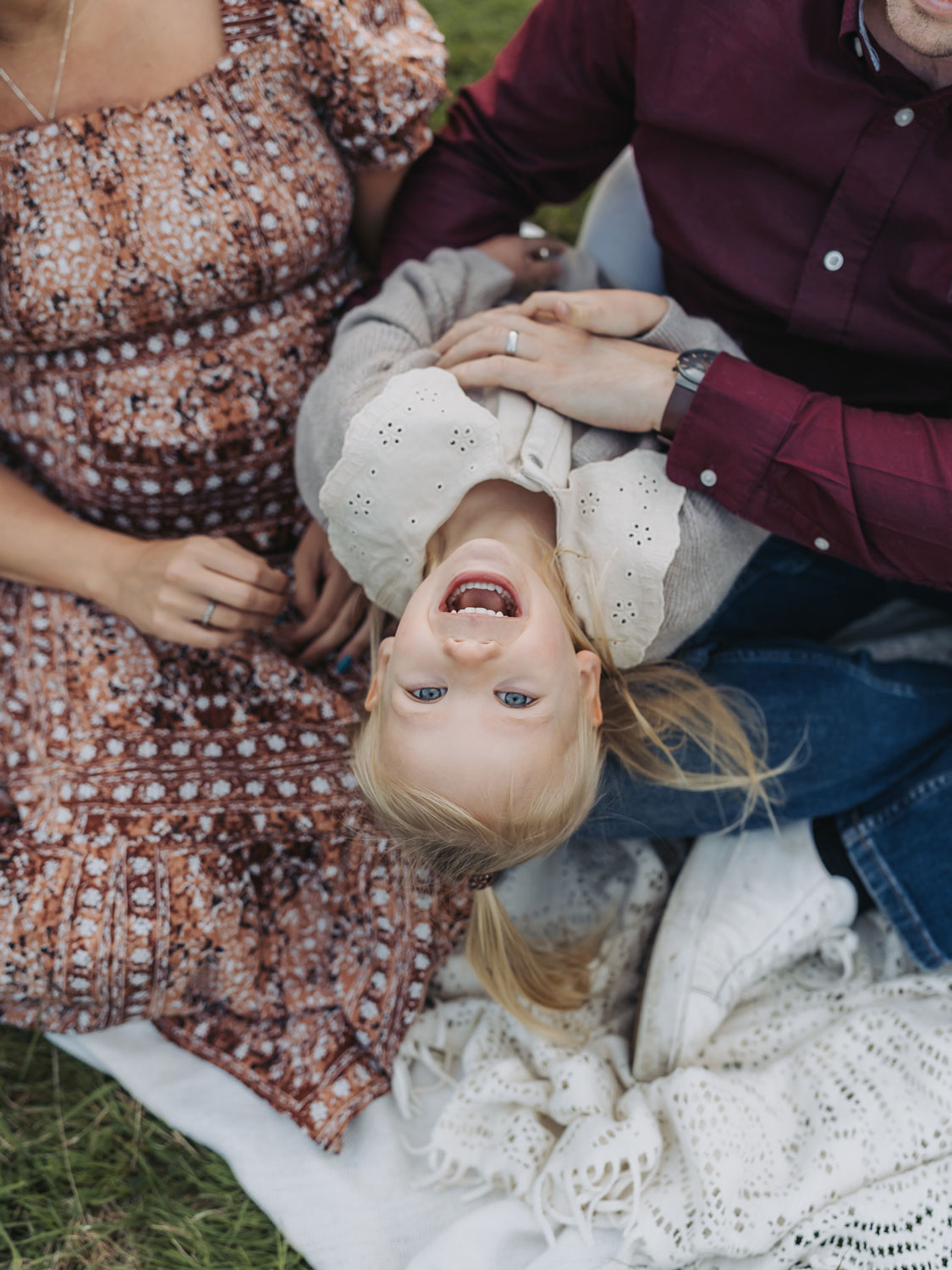 Outdoor golden hour maternity photoshoot with little girl upside down smiling at camera