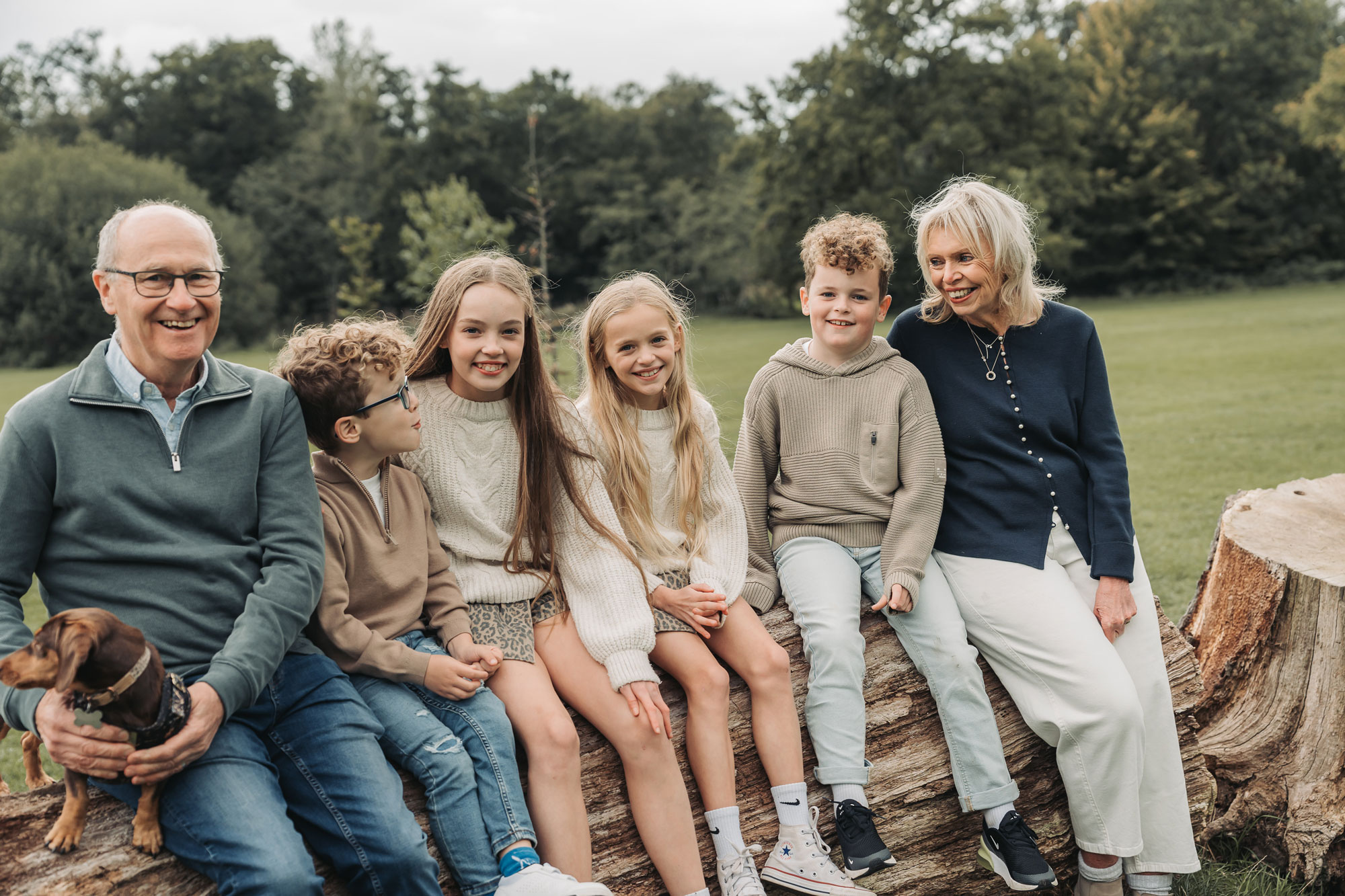 Photo from extended family photoshoot in Solihull park with grandparents and grandchildren sitting on log