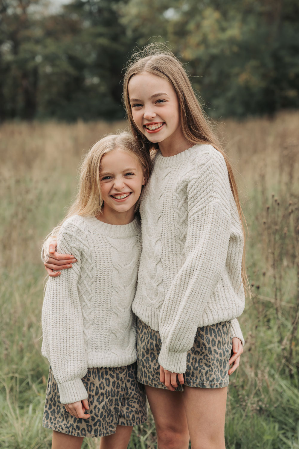 Photo from extended family photoshoot in Solihull park with sisters in matching outfits cuddling