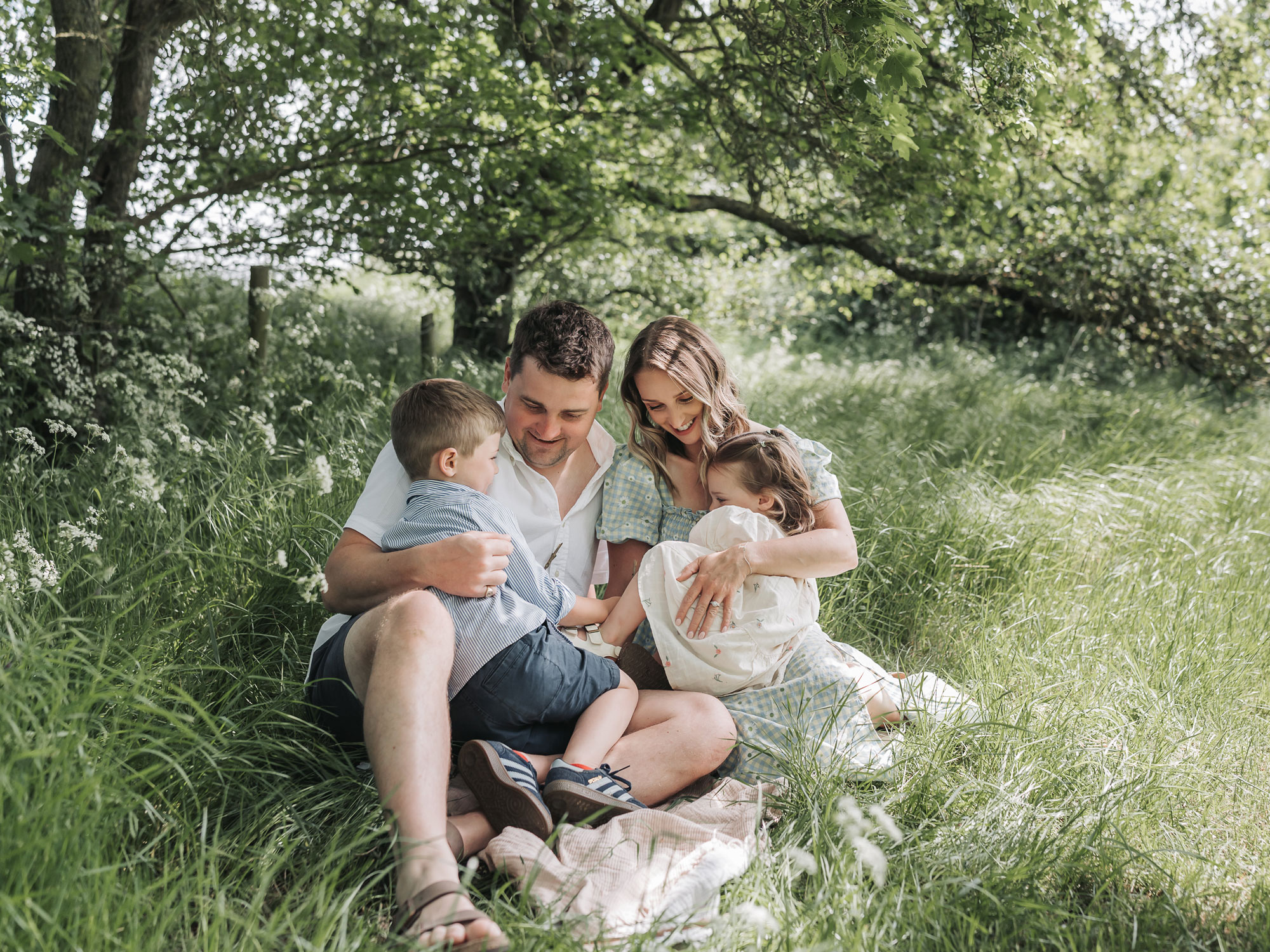 Family cuddling in long green grass together