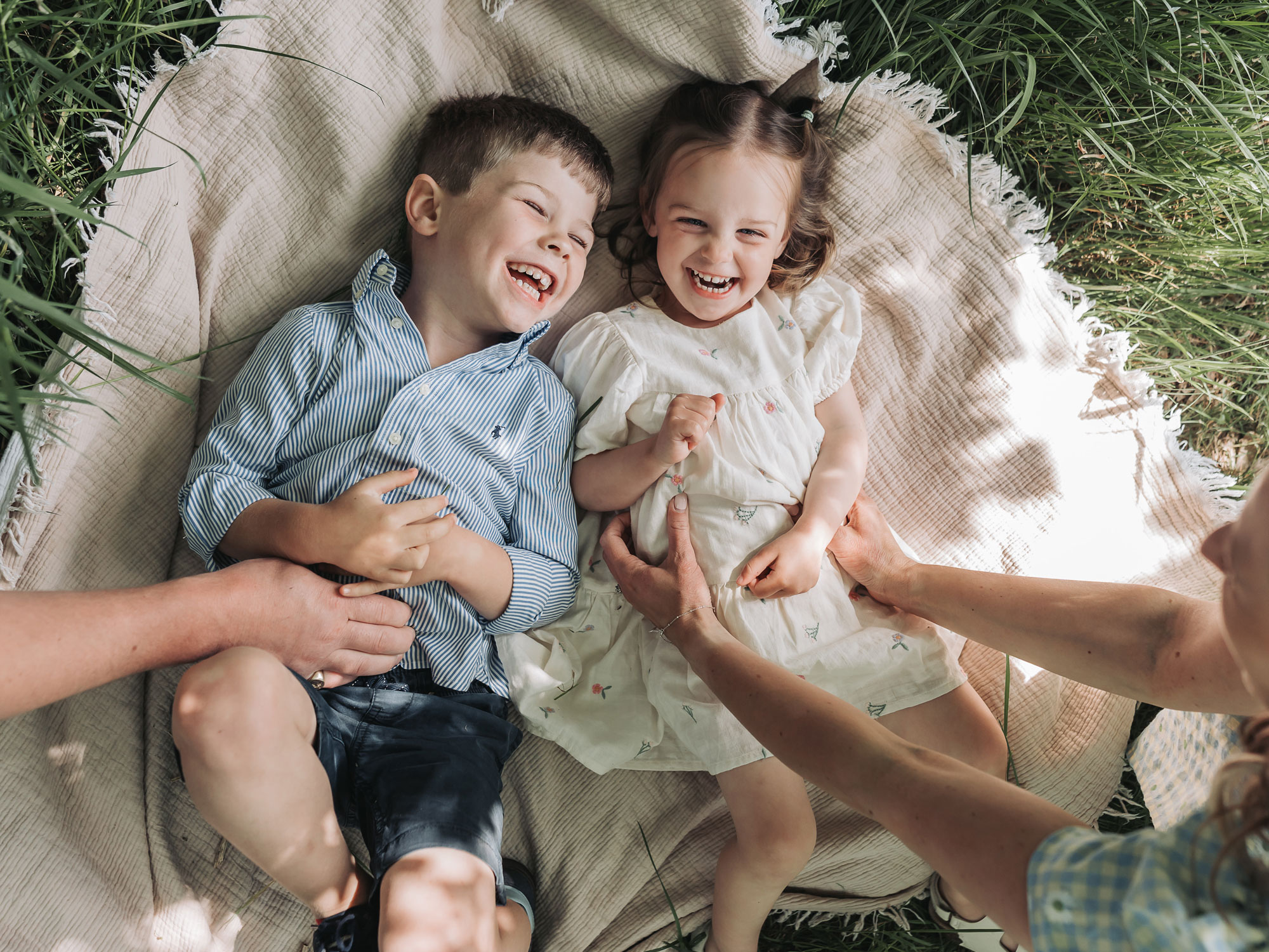 Children lying on blanket being cuddled during family photoshoot at Wootton Park