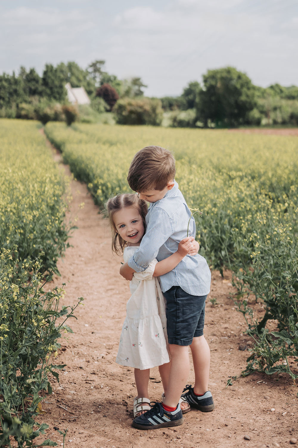 brother and sister cuddling in crop field at a family photoshoot in Warwickshire