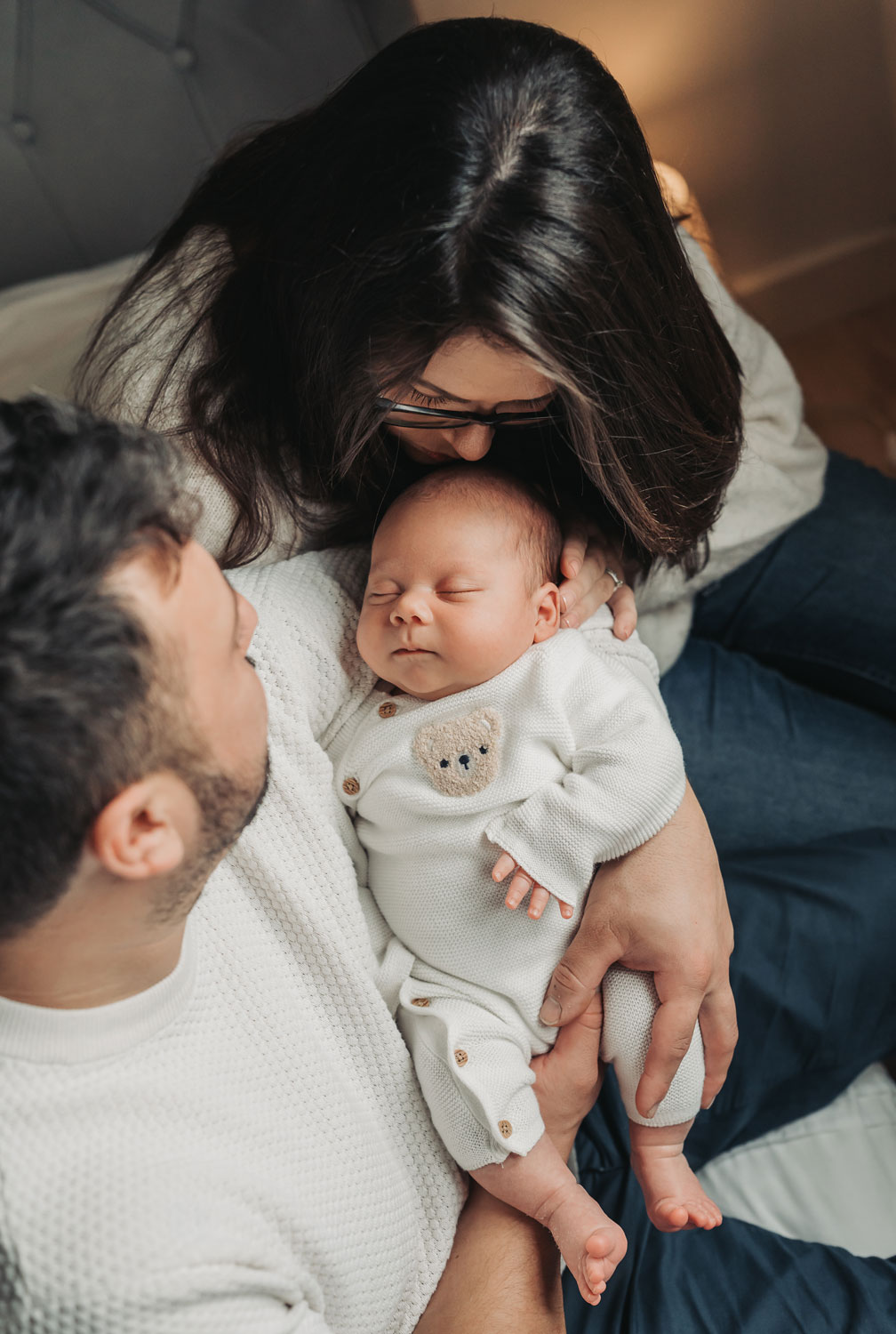 baby asleep in parents arms wearing teddy bear outfit