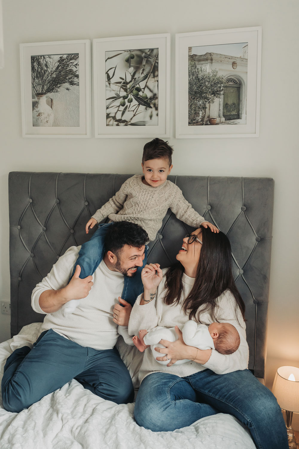 family on bed with toddler on dads shoulders