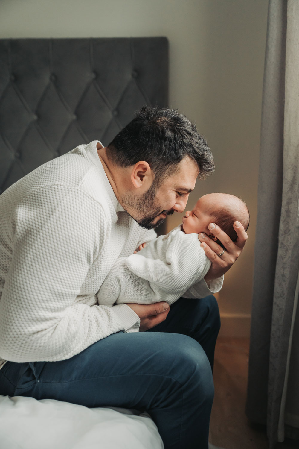 dad leaning over whilst holding newborn baby