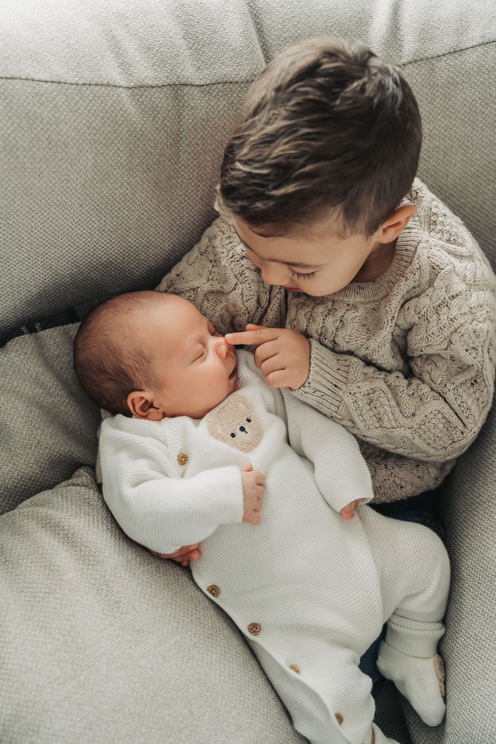 toddler brother holding baby and touching nose