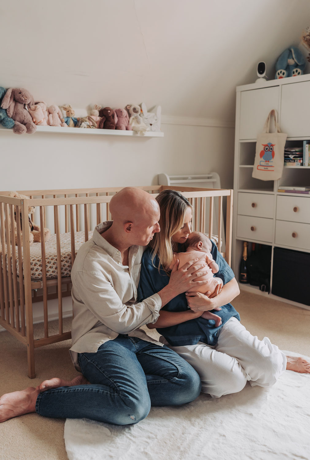 parents sat on nursery floor holding newborn baby