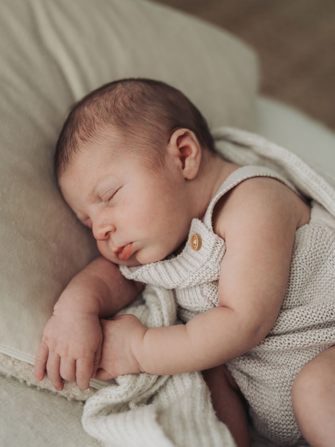 baby wearing knitted dungarees asleep lying on side