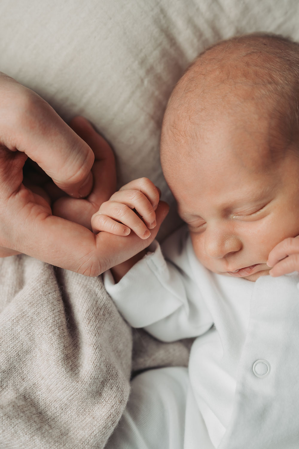 close up of baby holding parent's finger