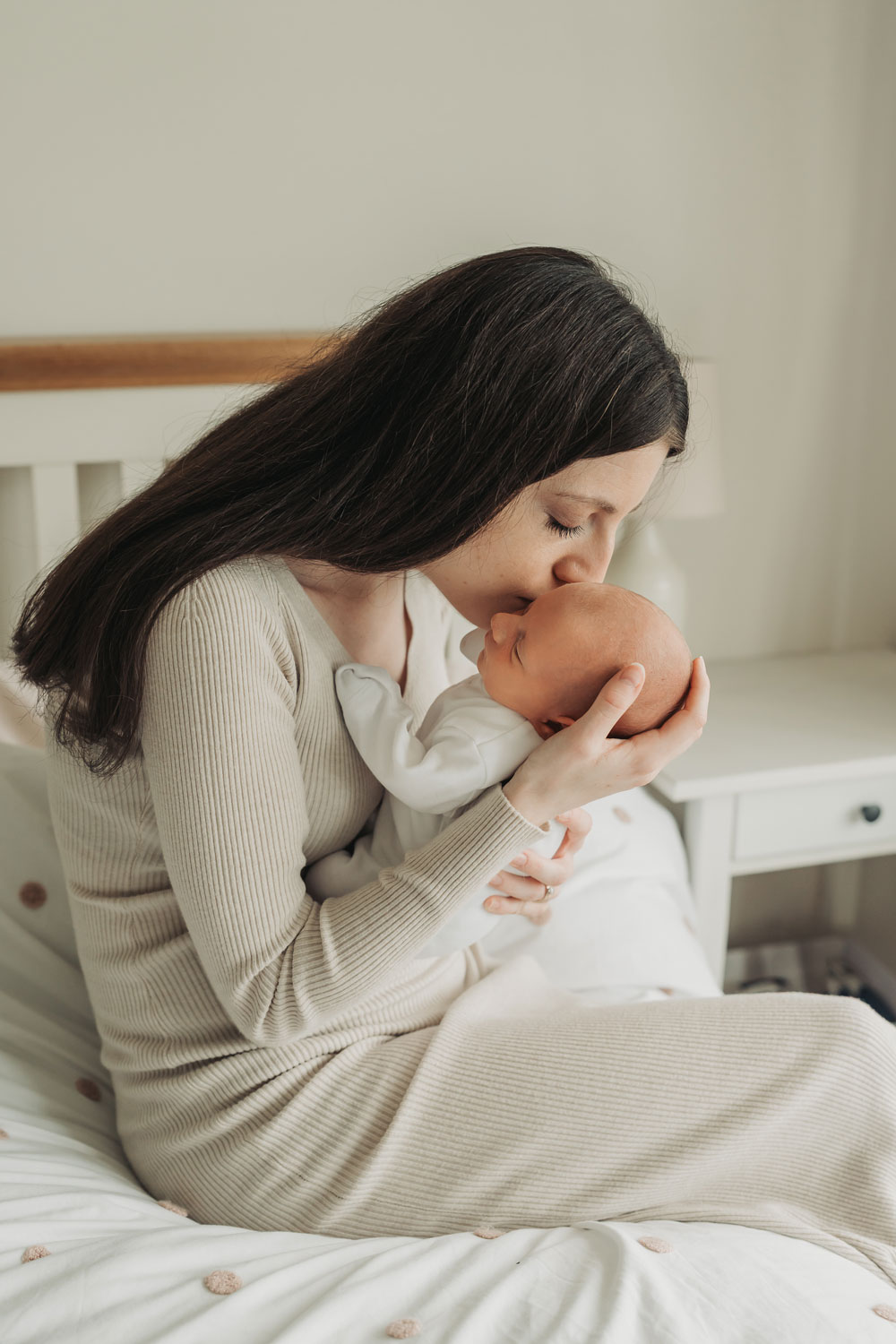 mum wearing beige dress kissing baby