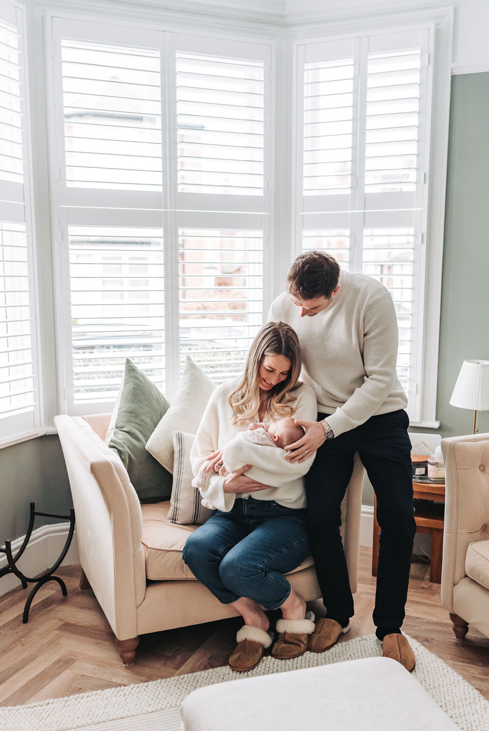 Leamington family sat on chair in window looking down at baby