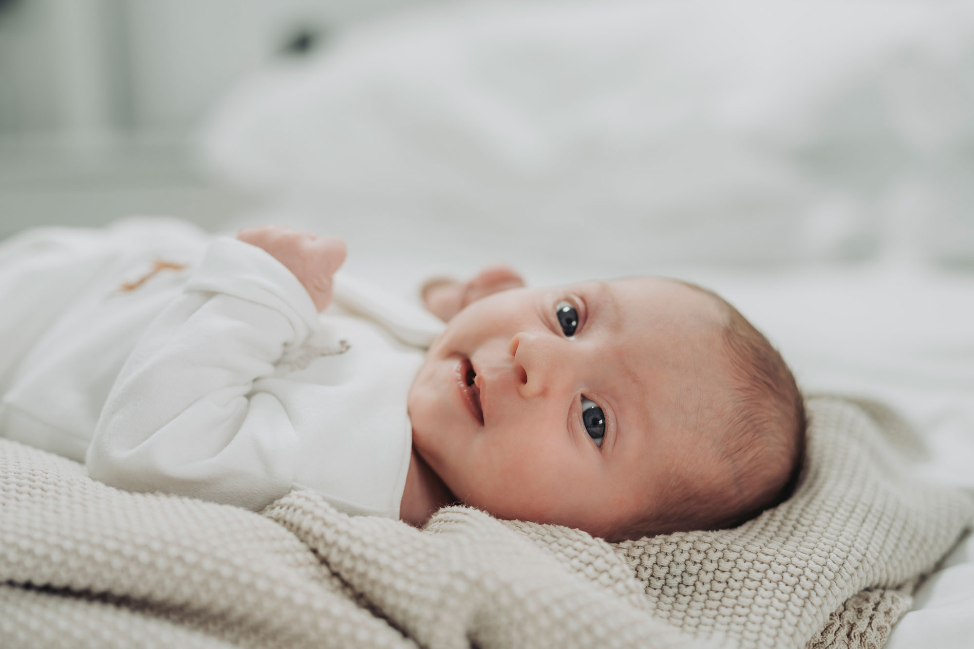 baby lying on blanket looking directly at camera