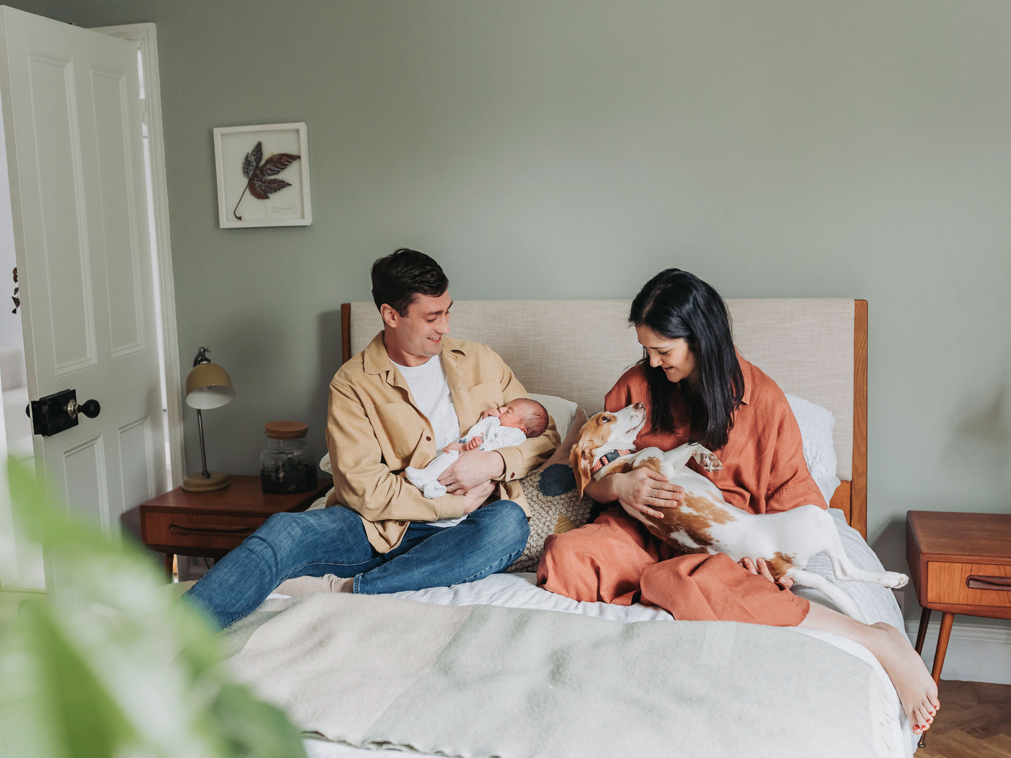 Family on bed holding baby and dog