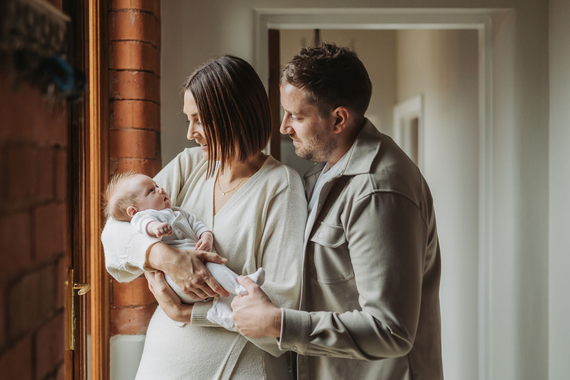 Mum and dad looking at newborn baby during a photoshoot at home in Coventry