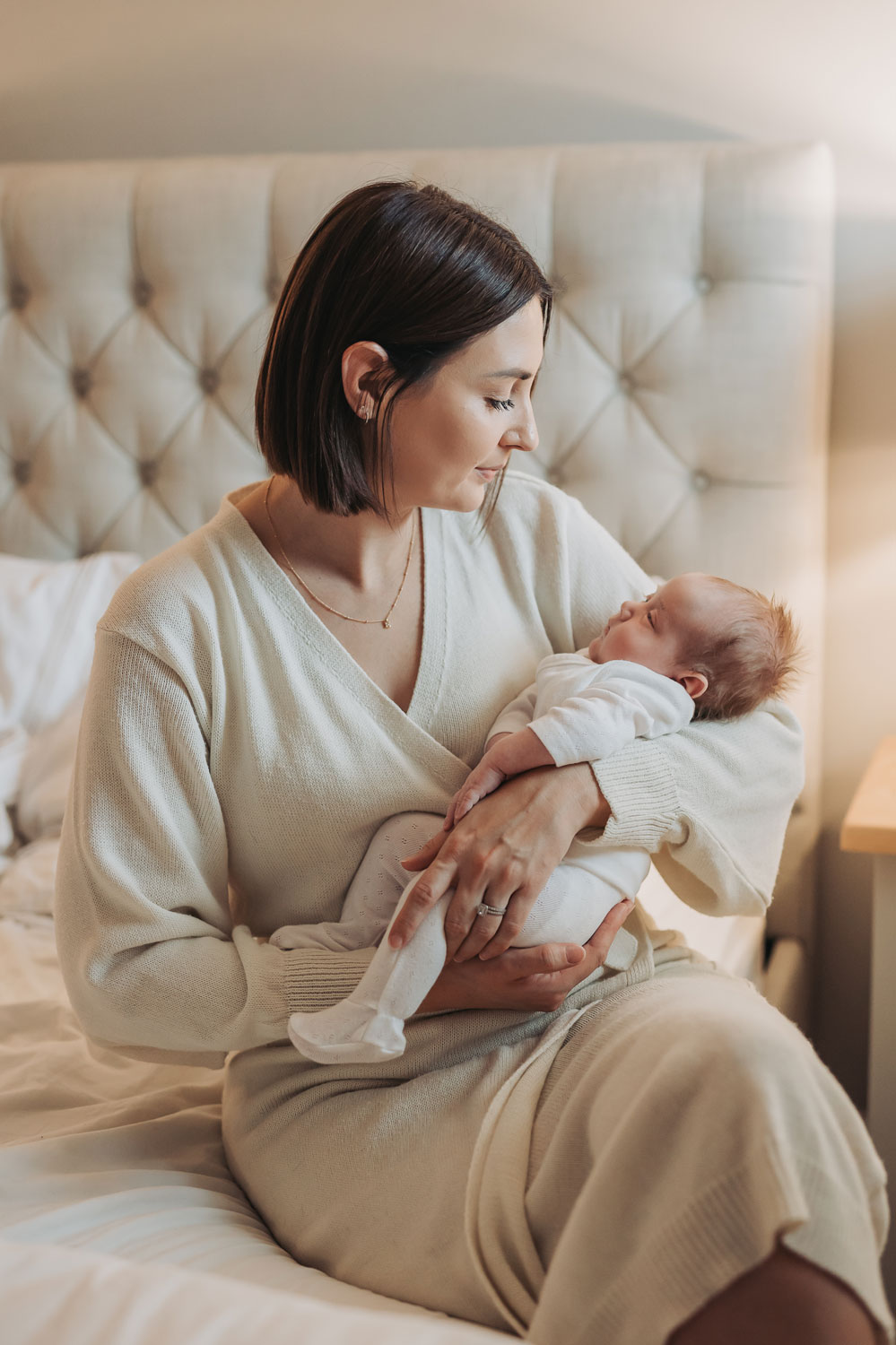 Mum on bed holding baby during an at home photoshoot in coventry