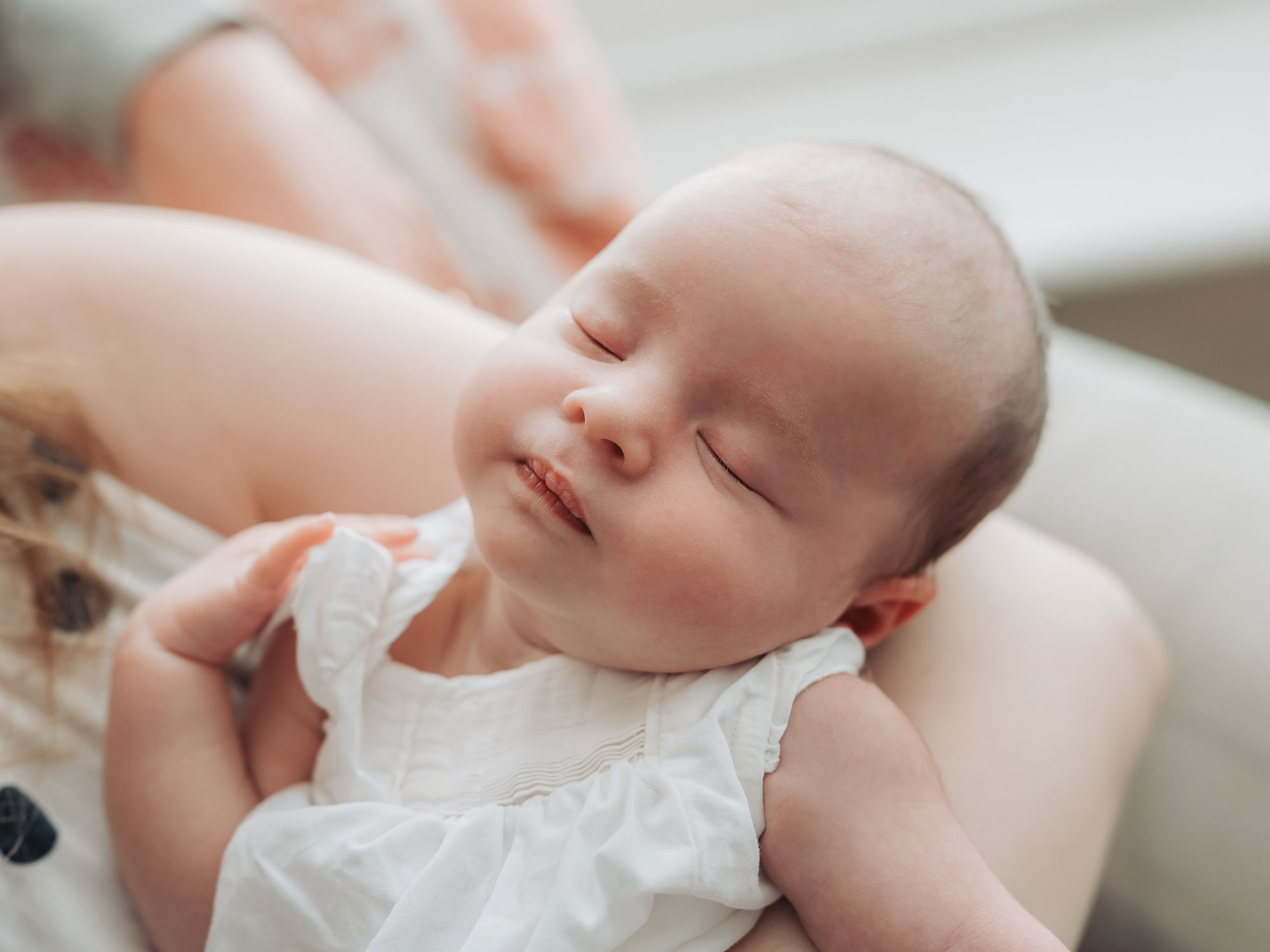 Close up of newborn baby asleep wearing a white top at photoshoot at home in Warwickshire