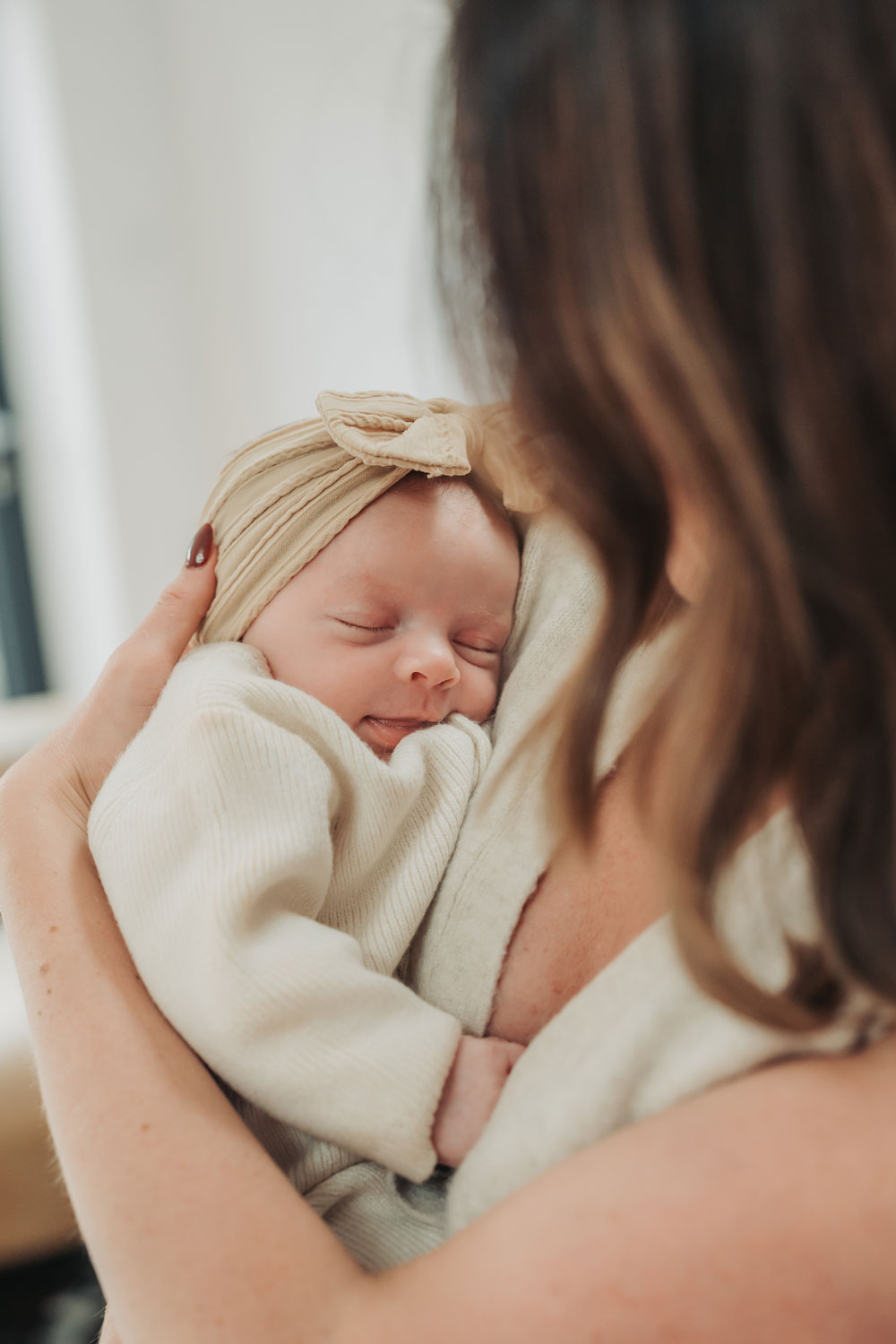 baby wearing headband asleep in mums arms