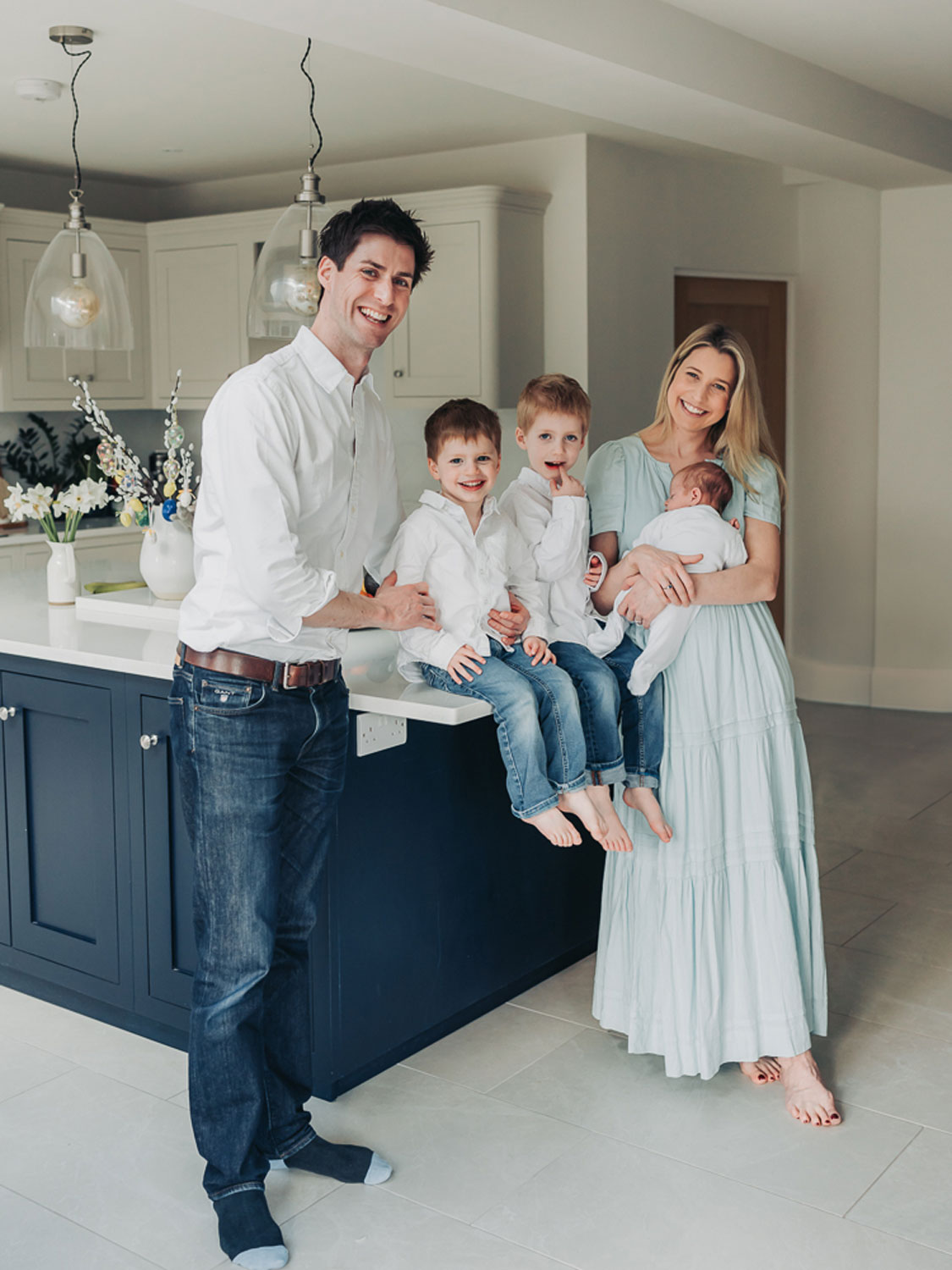family in kitchen smiling at camera wearing blue jeans and white shirt