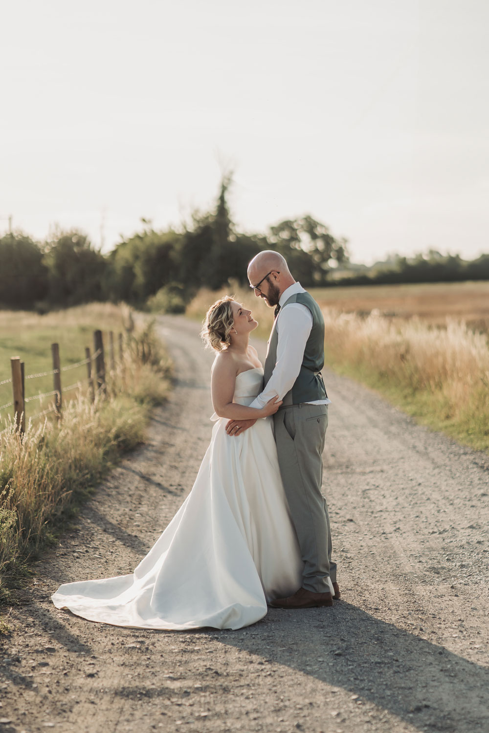 Golden hour couple portrait with bride and groom looking at each other arm in arm at Church Farm brewery wedding