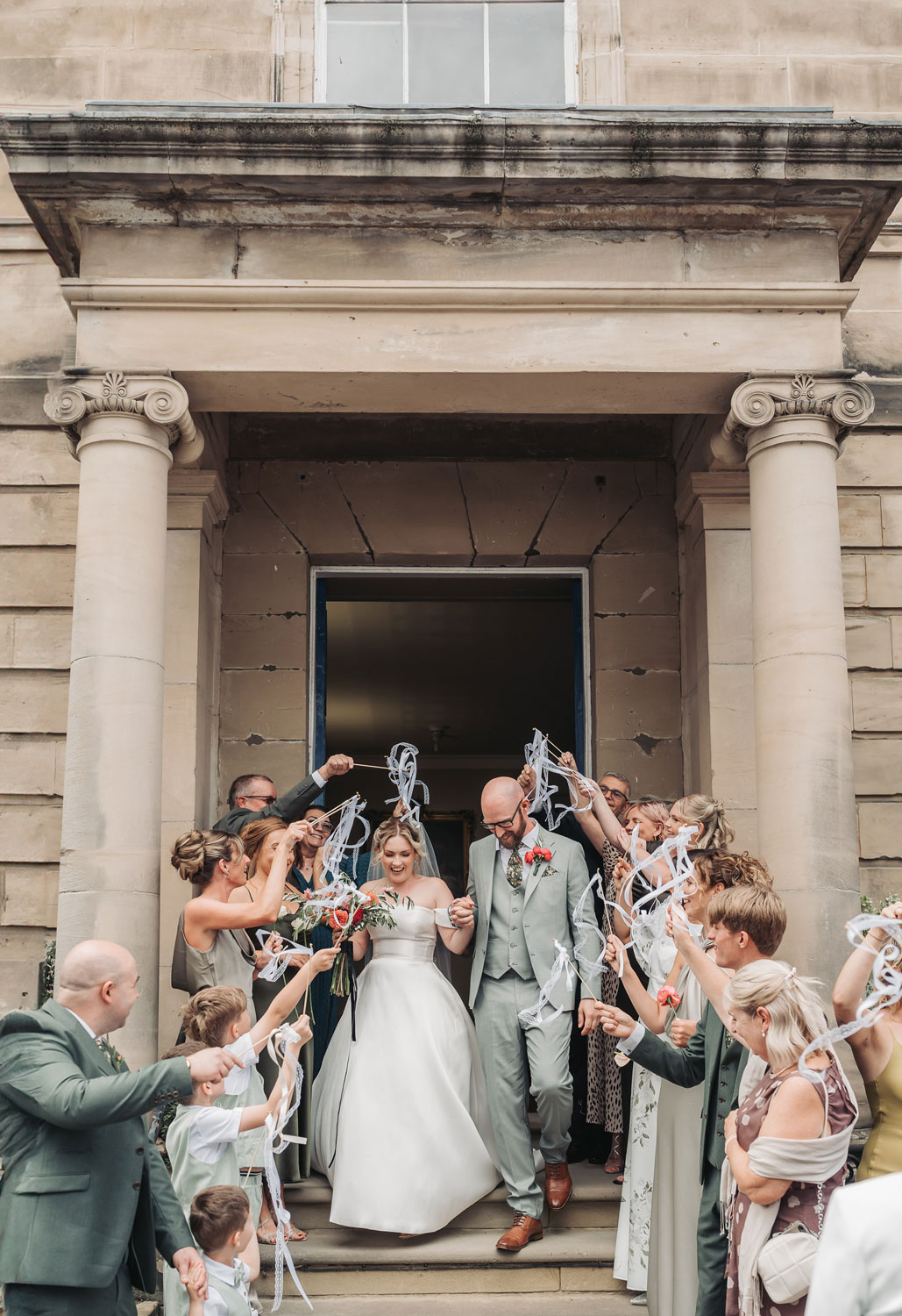 Couple walk through ribbon exit outside Warwick Registry office