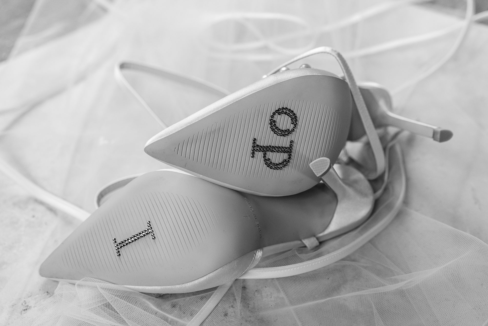 Black and white photo of wedding shoes saying 'I do' on the sole