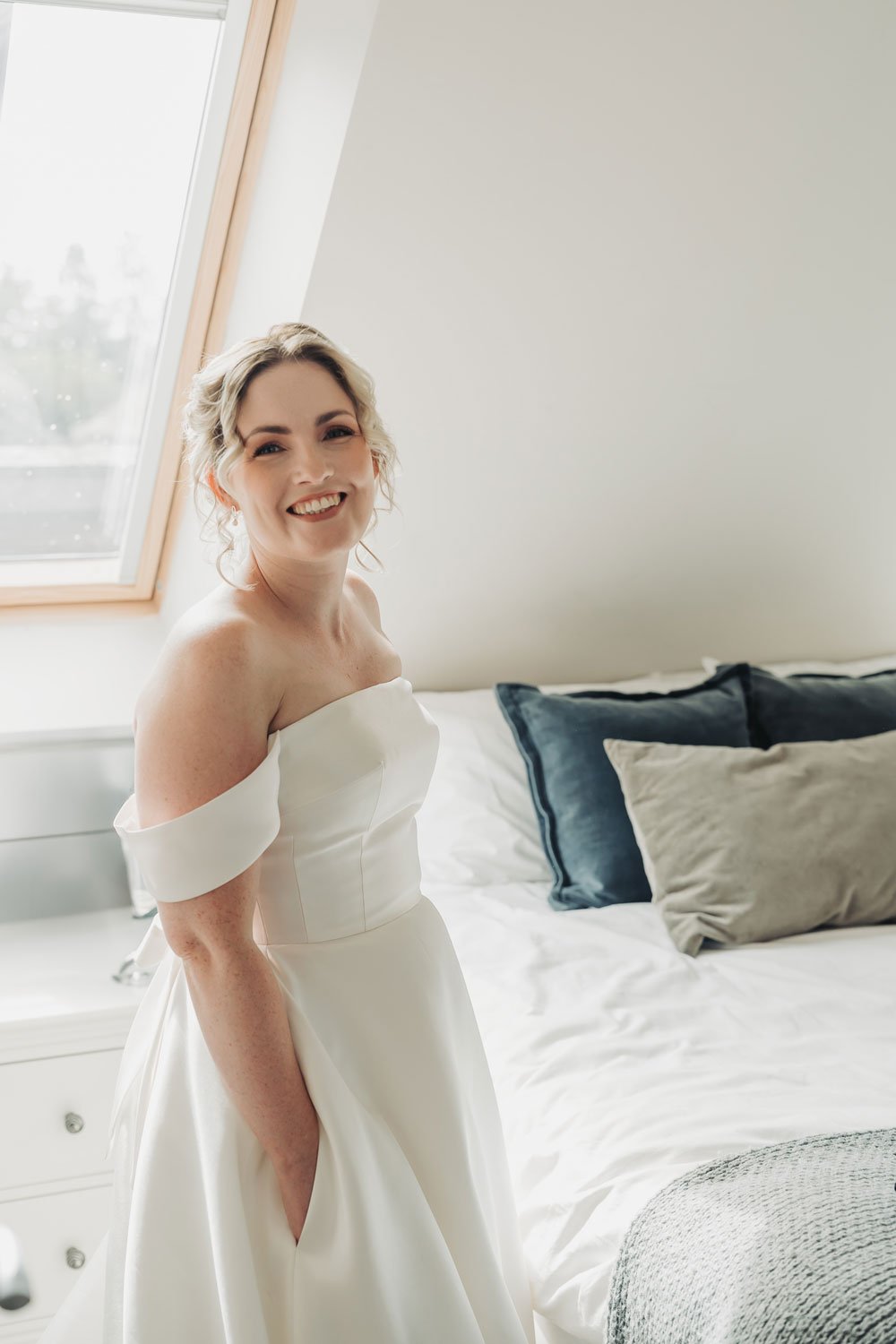 Bridal portrait with bride smiling at the camera with hands in pockets