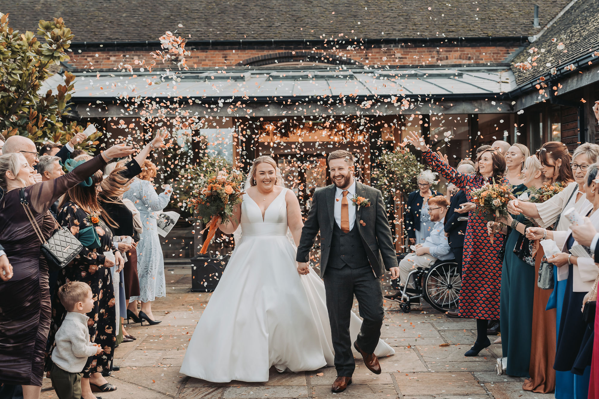 Couple walking through confetti at Mythe barn autumn wedding