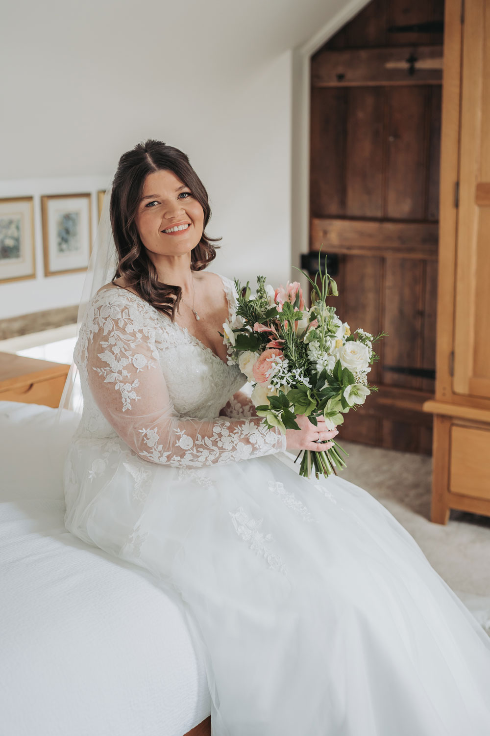 Bridal portrait sitting on the bed with bouquet
