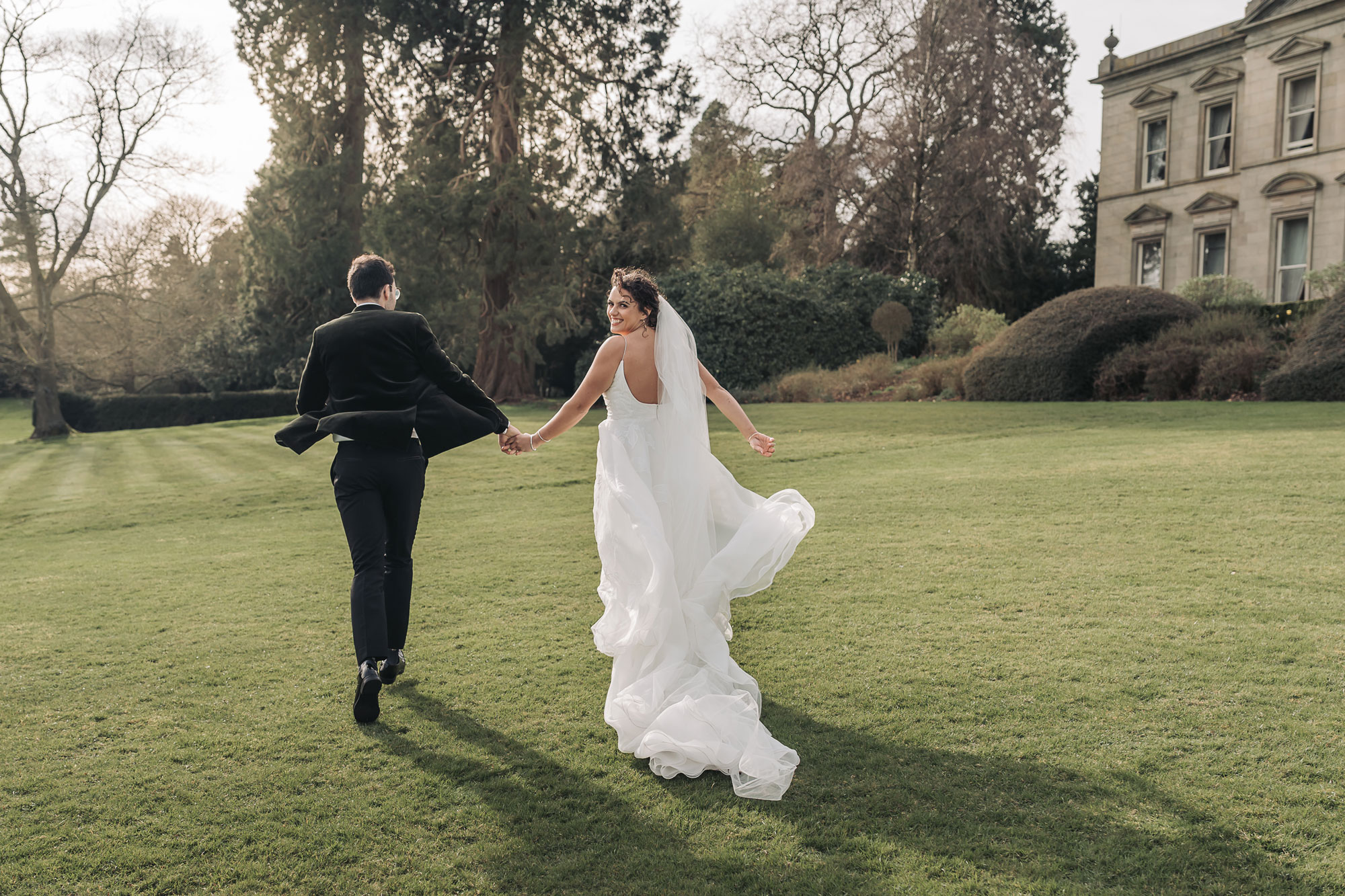 Kilworth house wedding with couple running across the lawn together hand in hand