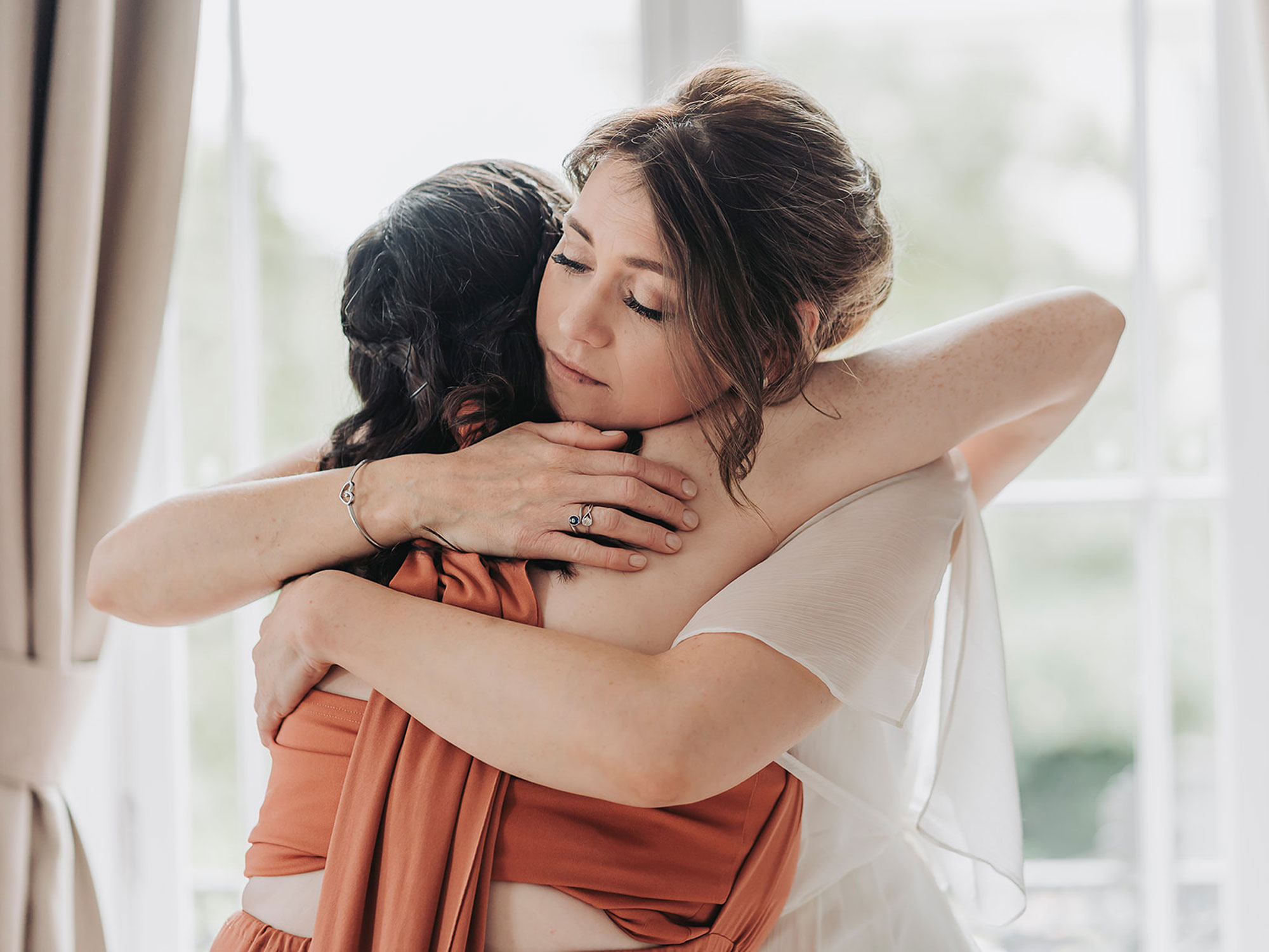 Bride hugging bridesmaid at Leamington wedding