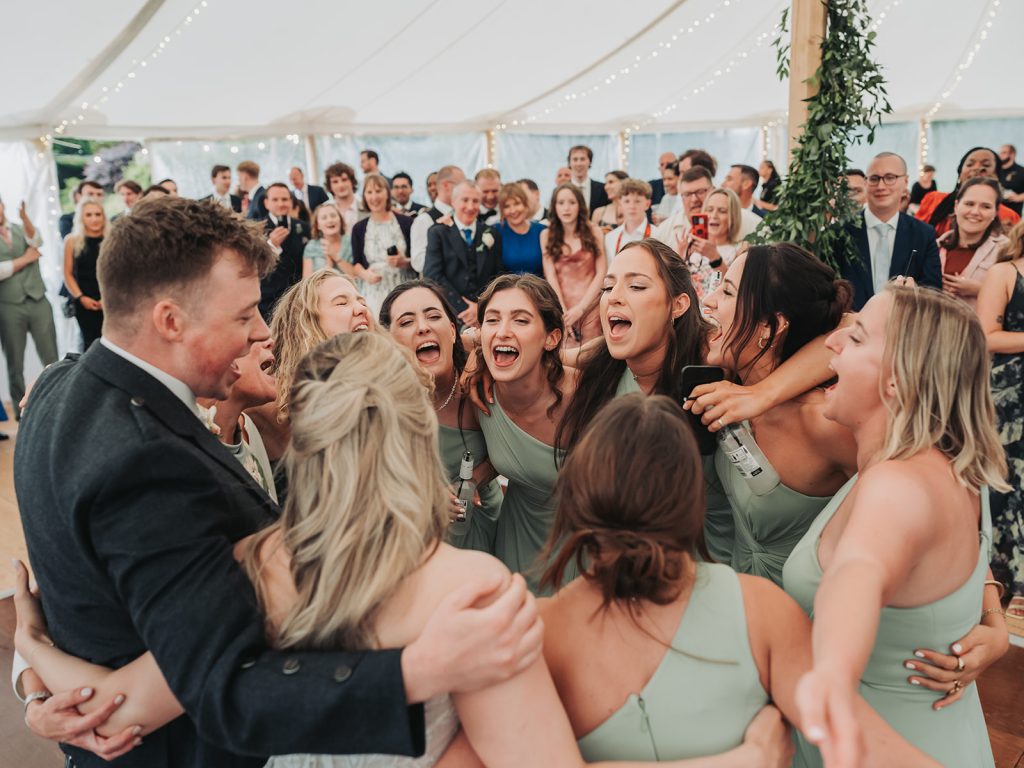 Bridesmaids singing in a circle on dancefloor