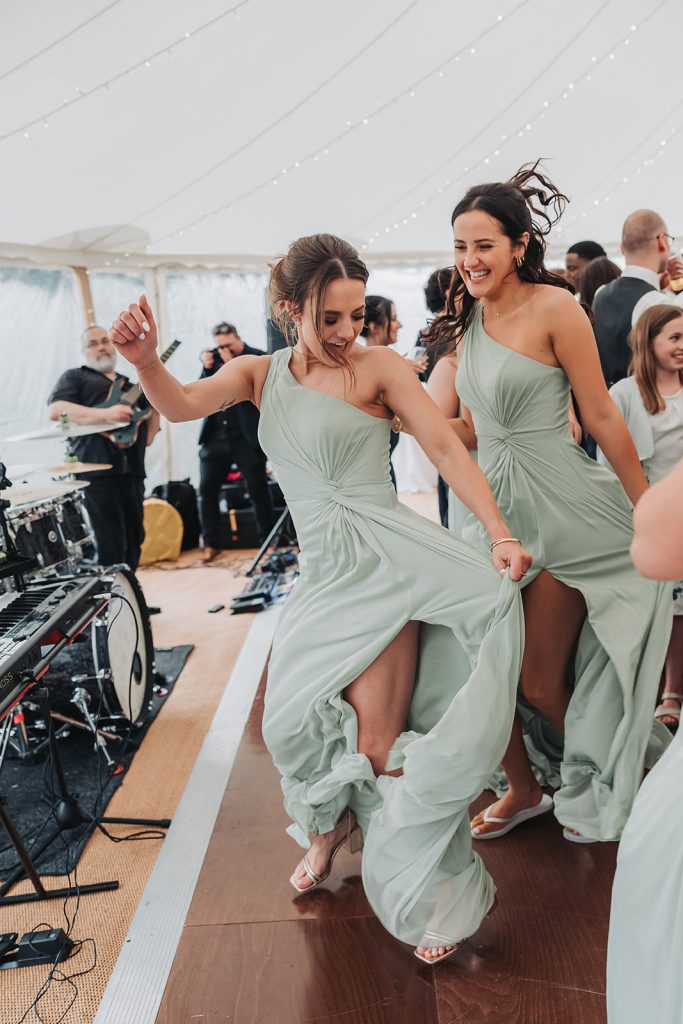 Bridesmaids swishing their sage green dresses on dancefloor