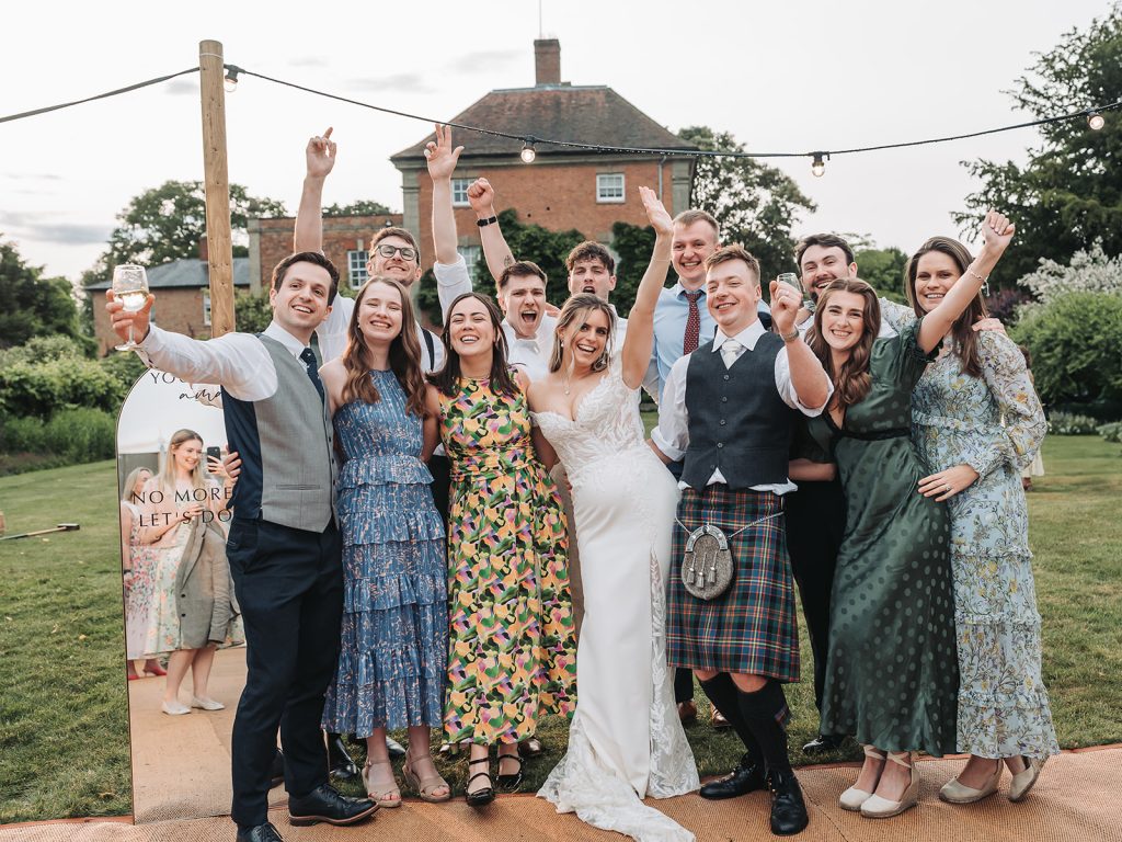 Bride, groom and wedding guests group shot with arms up high
