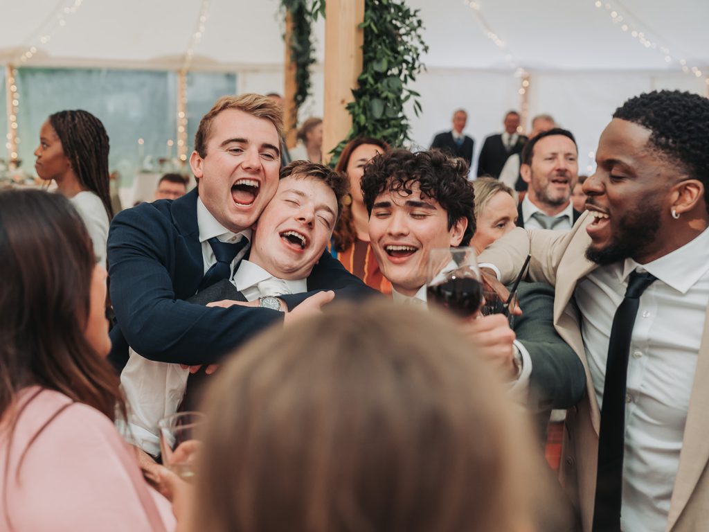 Wedding guests on dance floor singing and hugging