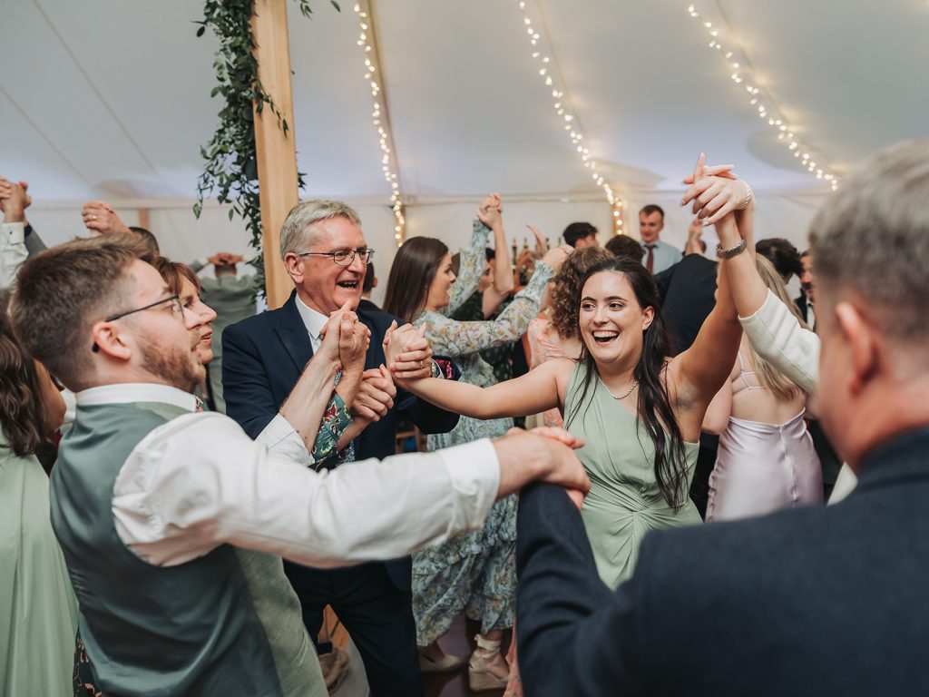 Wedding guests dancing a cèilidh looking happy