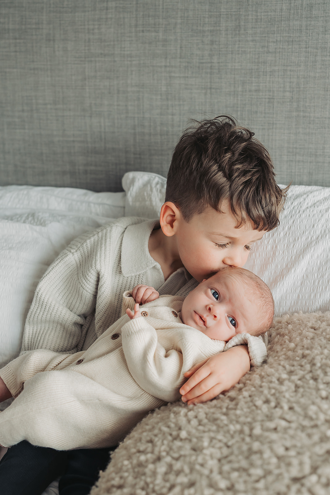 Little boy kissing new baby sister during newborn photoshoot