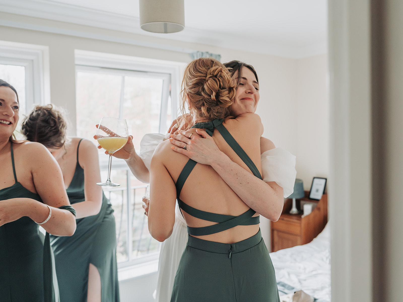 Bridesmaid wearing emerald green dress hugging bride