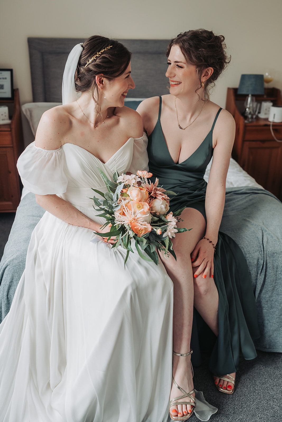 Bridesmaid and bride smiling and laughing at eachother