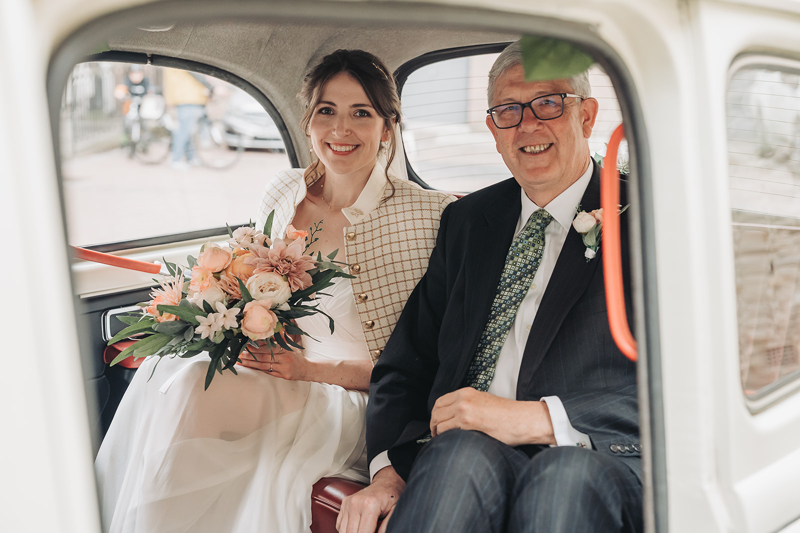 Bride and father in wedding car smiling at camera