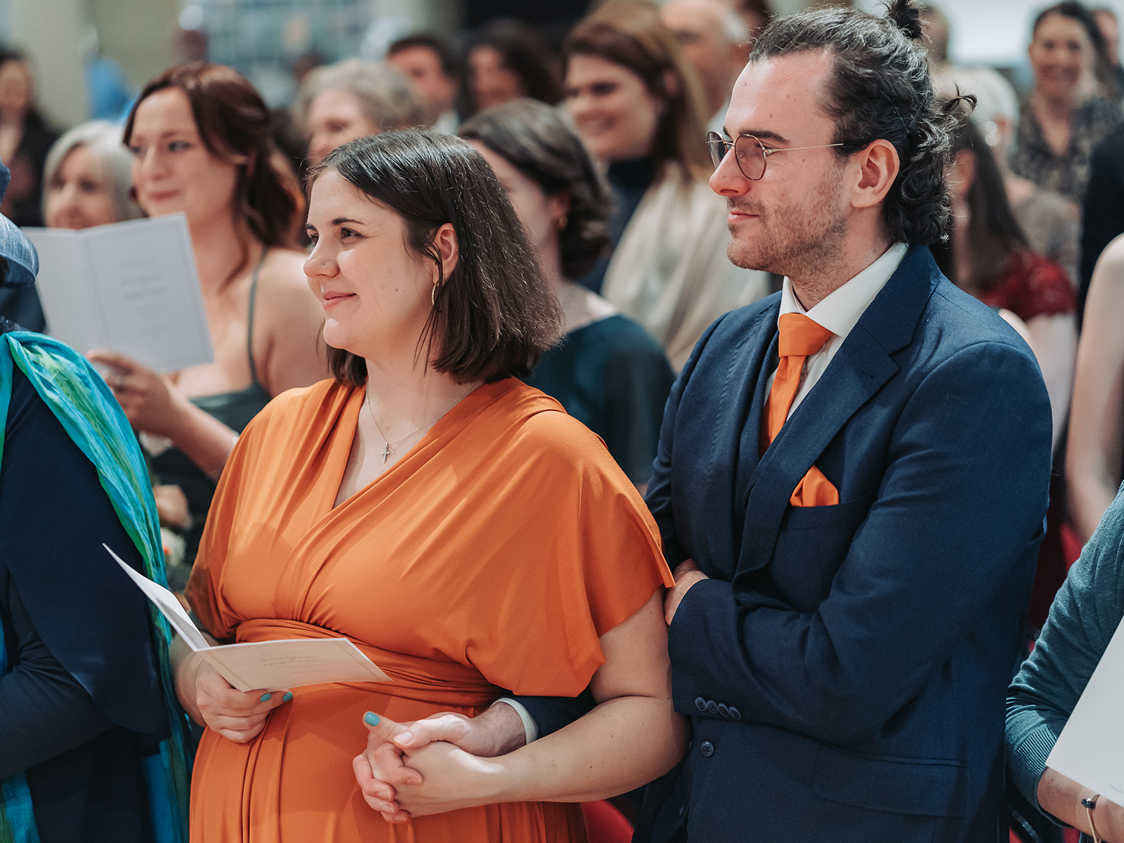 Wedding guests holding hands wearing orange