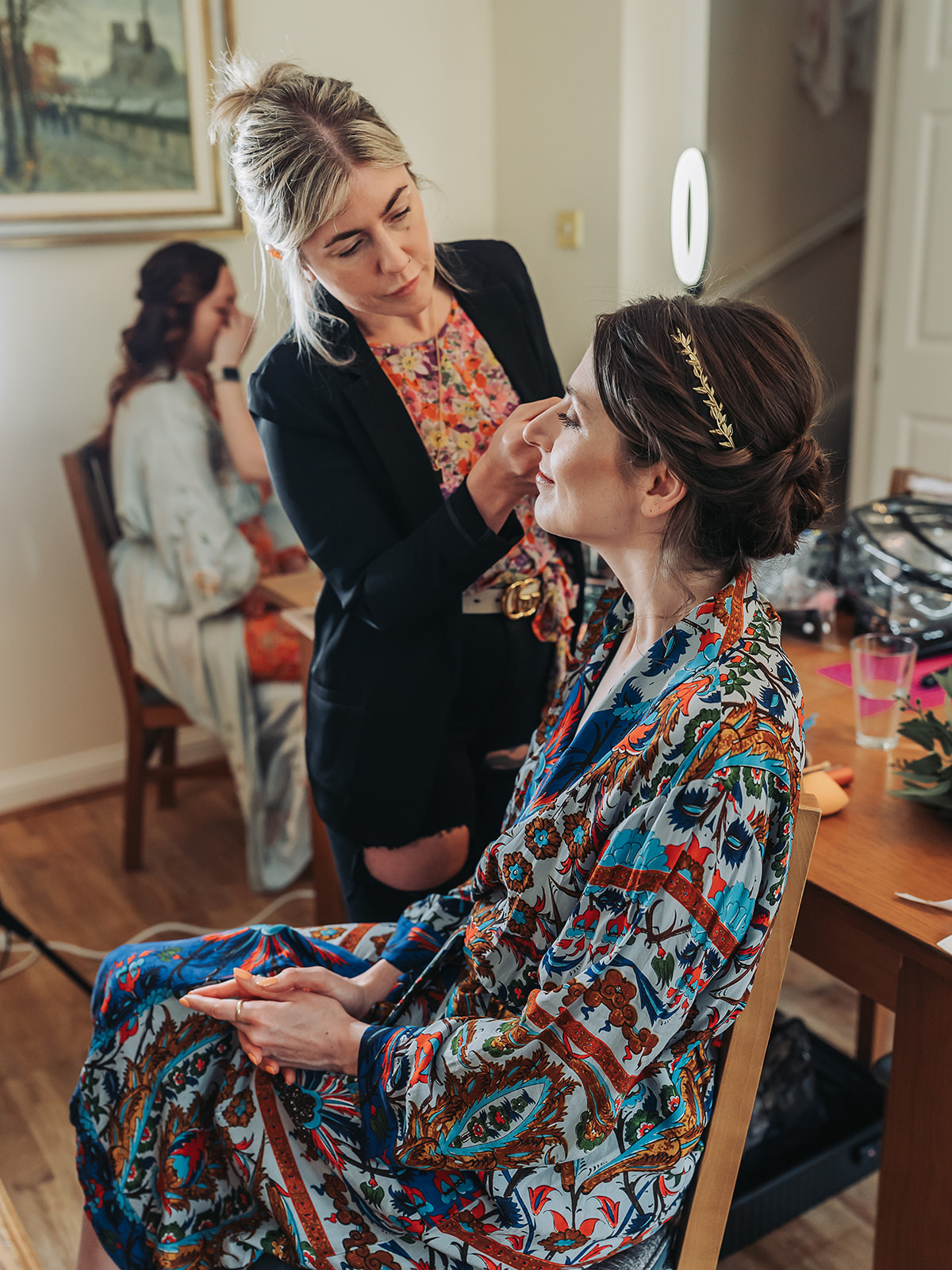 Bride in bright colourful patterned dressing gown having make-up done