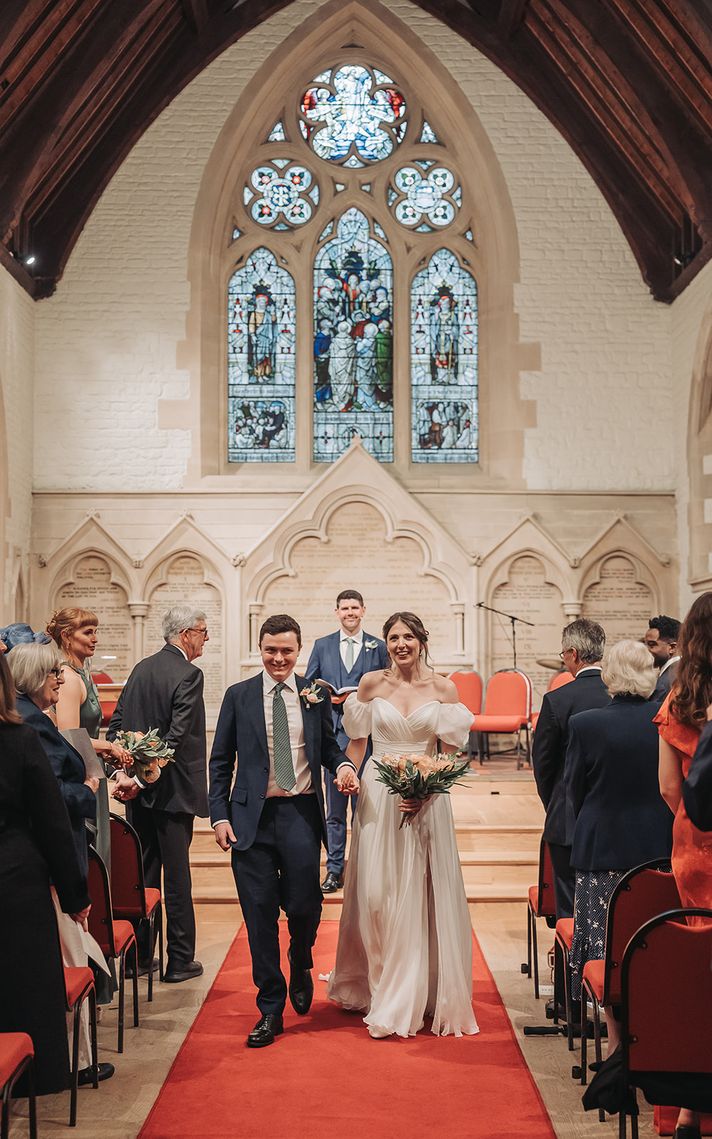 Bride and groom walking down the aisle looking happy at St Ebbe's