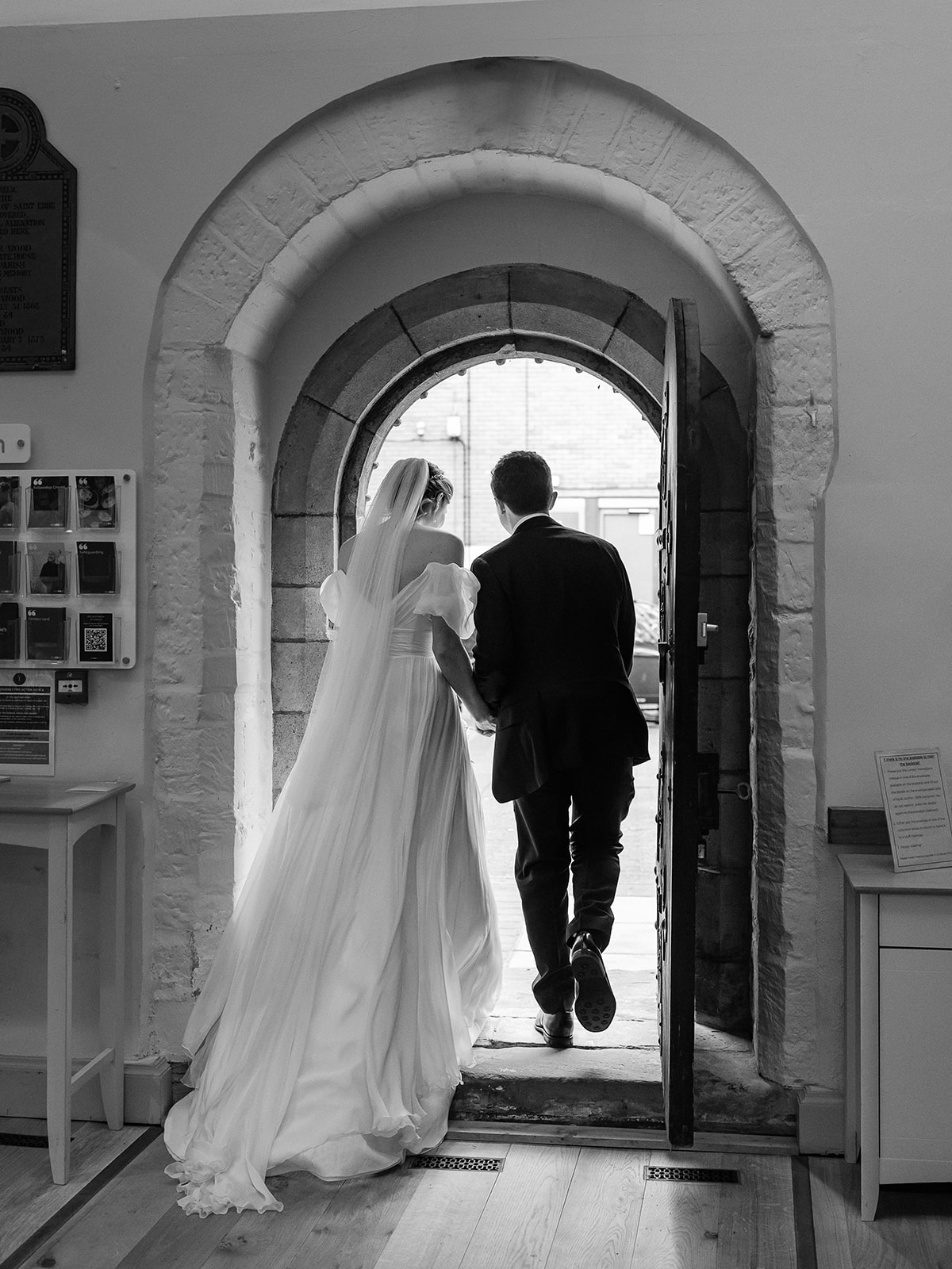 Black and white photo of bride and groom walking out of the door at St Ebbe's